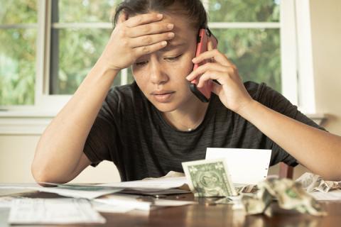 Young woman with US cash and mobile phone, financial difficulty