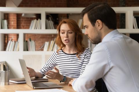 A man and woman discuss over a laptop