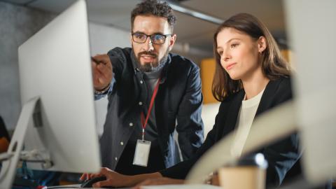 A lecturer points to a computer screen while a student listens