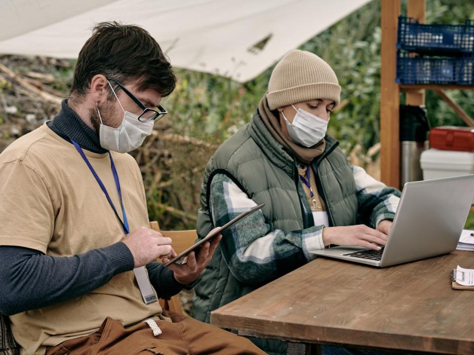 Image of two people at a refugee volunteer centre working online