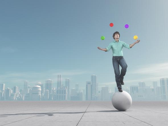 Man on ball juggling balls in front of a city