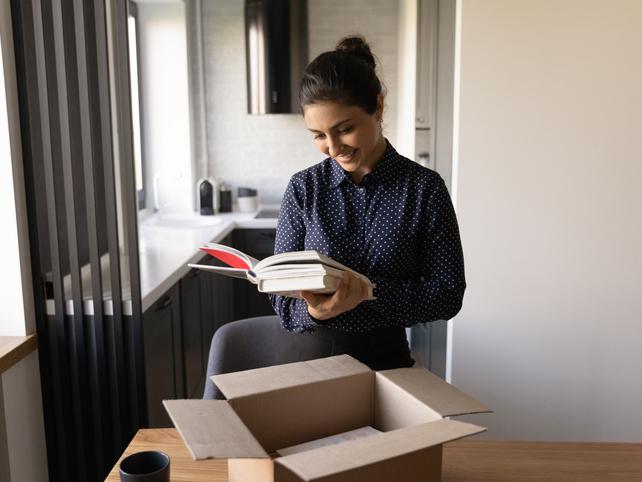 Young Indian woman opens a carton of books