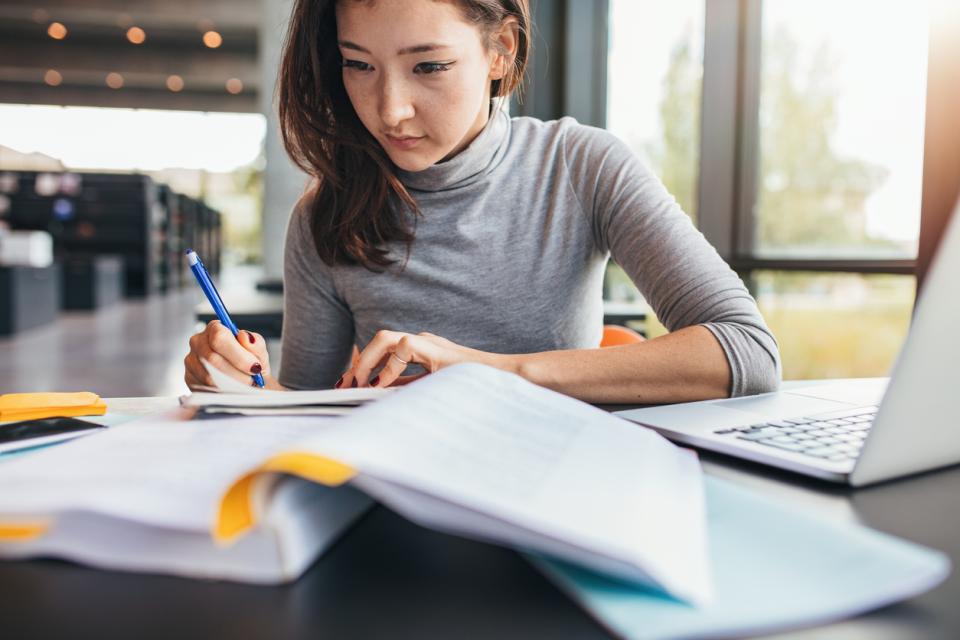 Female student working while referring to books