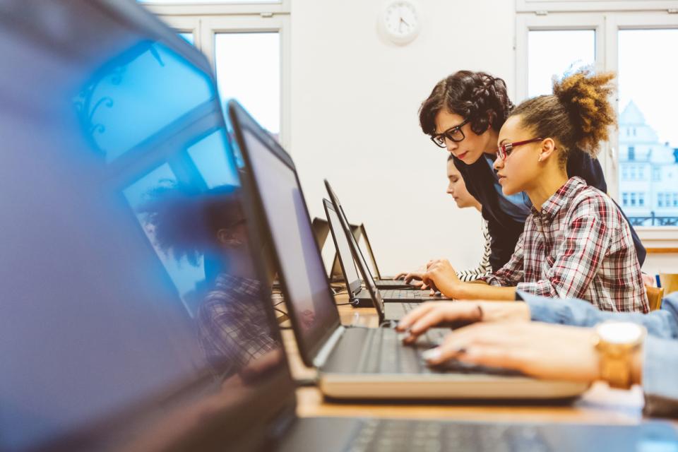 A teacher shows a students how to code