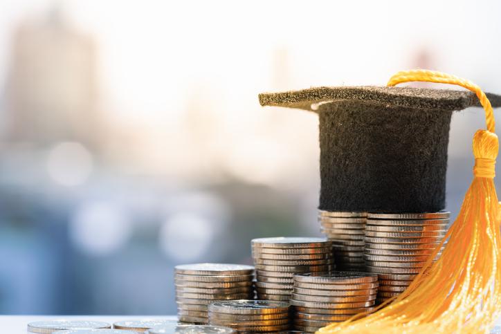 A motarboard sits atop a pile of coins