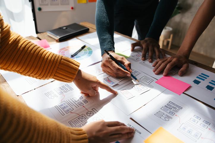 Two people discuss diagrams laid out on a table