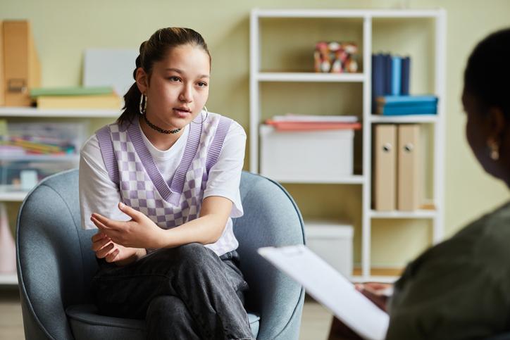 A student talks intently to an out-of-focus lecturer