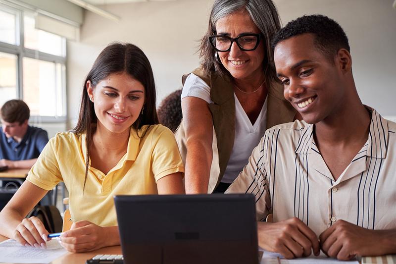 University teacher helping two multiracial students