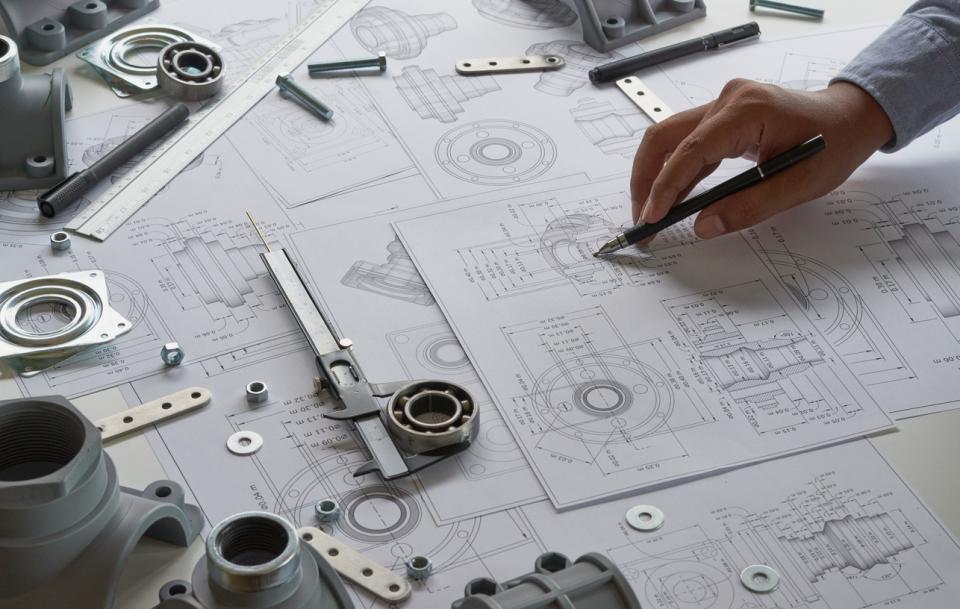 A hand sketching prototype designs amongst rulers and other tools