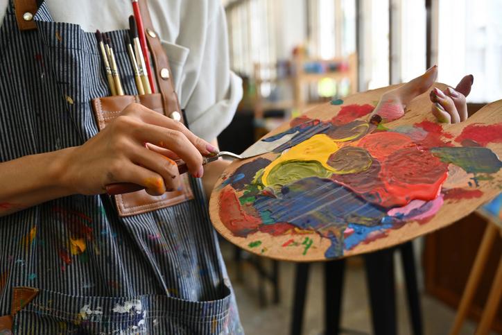 An artist mixes paints on a palette