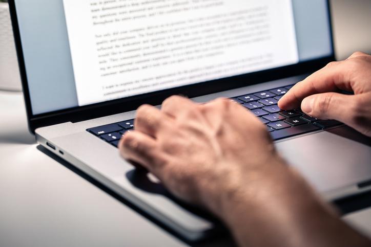 An academic works on a document on a laptop