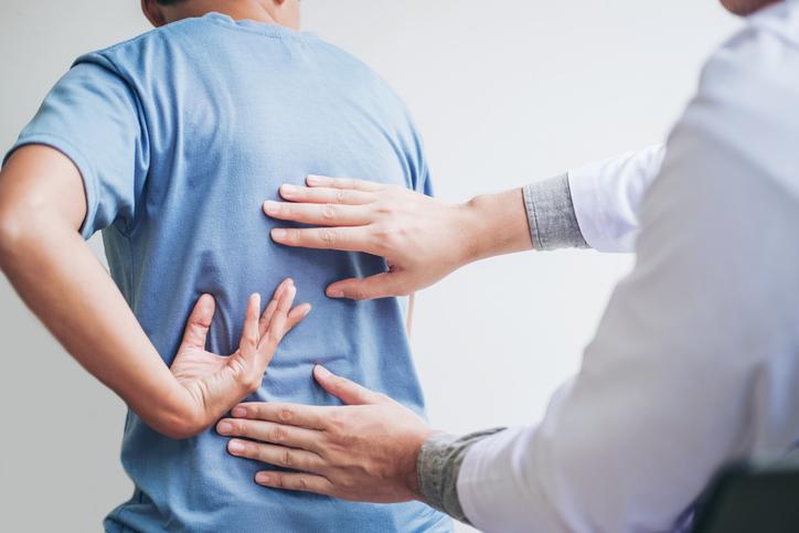 A physiotherapist inspects a patient's back