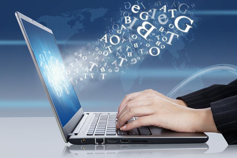 Laptop with cloud of letters coming out of screen