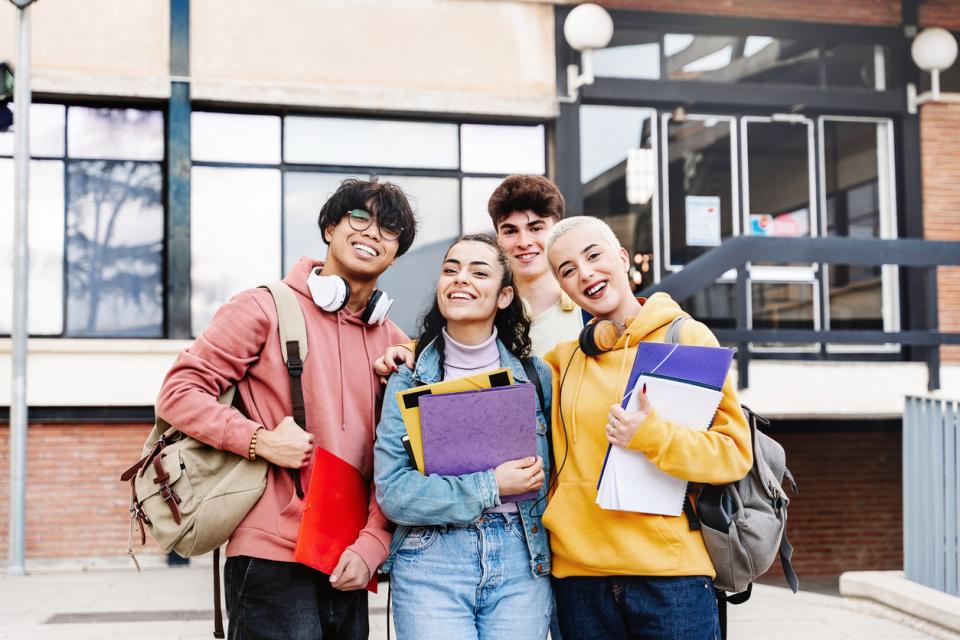 A group of smiling university students outside a campus building