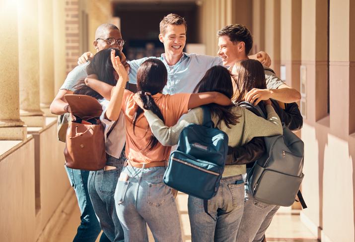 A group of students hug on campus