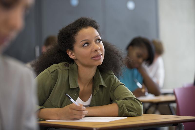Black female student looking thoughtful writing