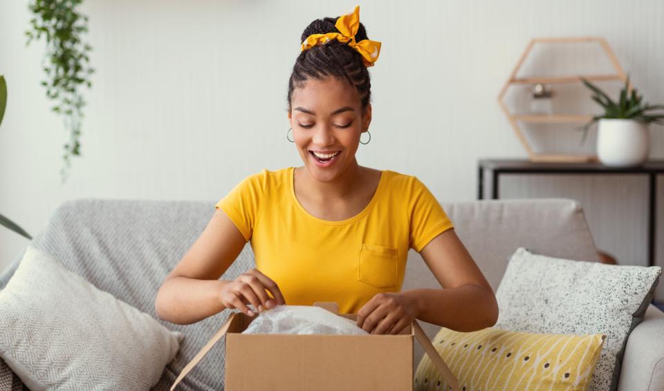 A woman opening a package with a surprised expression on her face