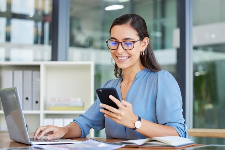 A woman smiles as she checks her phone