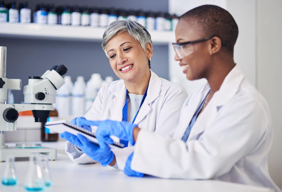 Two female scientists consulting a document in a lab 