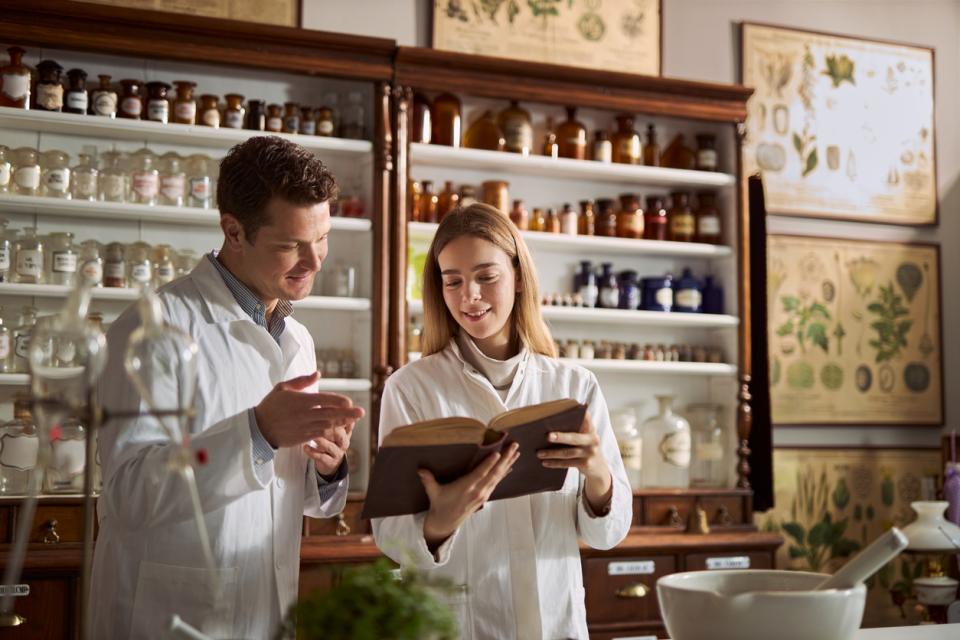 Two chemists in a lab consulting a training manual