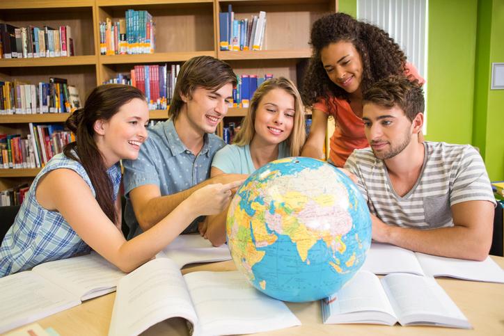 Students point at a globe