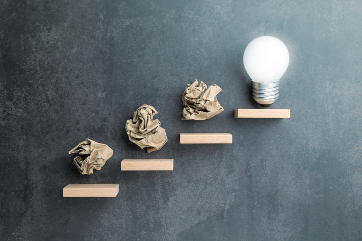 An illustration of screwed up bits of paper leading to a lightbulb moment