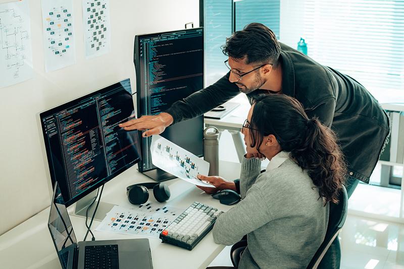 Two people looking at code on a computer screen