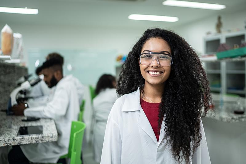 Female high school student in lab wearing a white coat
