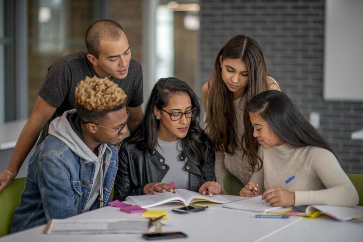 Students gather around a table to work together