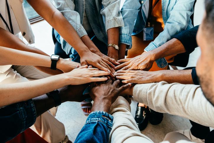 Team members place their hands in a circle