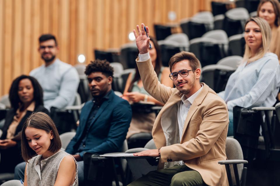 Student raising their hand to speak in a lecture