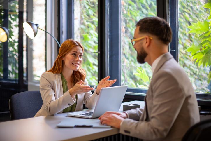 Two people talk over a desk