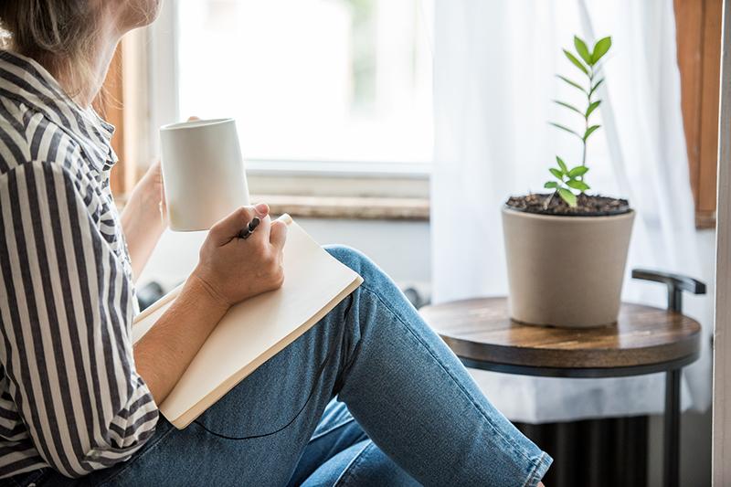Woman writing in journal by window
