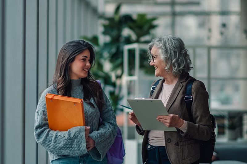 Young female university student meeting in all with older female supervisor