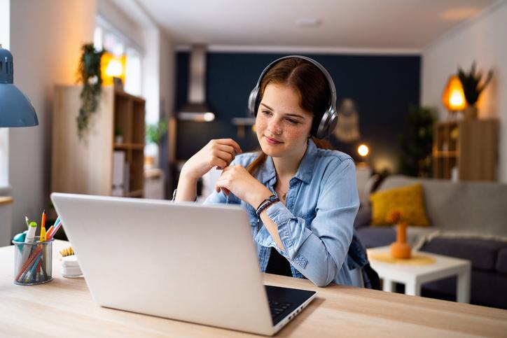 A student with headphones on her laptop 