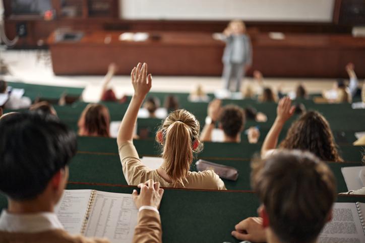 A student raises a hand in a lecture hall
