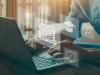 Man at laptop with symbols of academia, how to write a successful book proposal