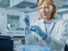 Woman researcher with pipette wearing protective glasses