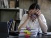 professional woman in office with laptop with head in hands