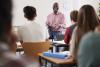 A male lecturer talks to a class of students