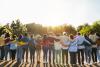 A multigenerational group of people link arms and gaze into the sunset