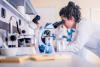 An early career researcher looking through a microscope in a lab