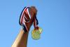 Hand holding three gold medals