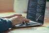 Close-up of hands coding on a laptop