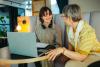 A mentor helps a student over a laptop