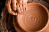 Hands work on a clay pot