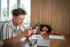 A young academic plays a game on his phone while his co-worker naps on the desk
