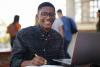 Young black male students working outside on laptop