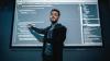 A teacher stands in front of a projector screen