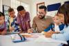 Male teacher working with multiracial primary school class